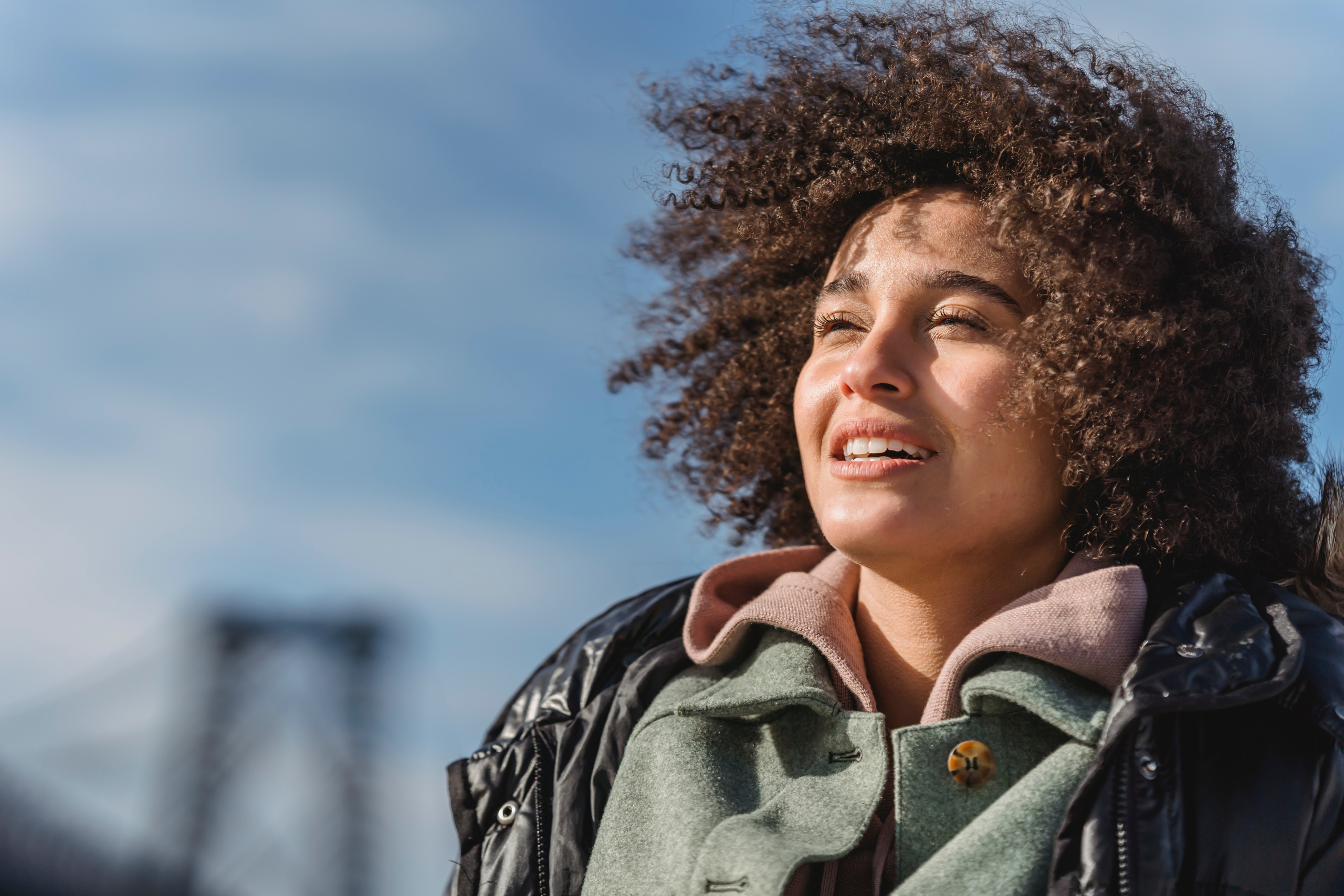 woman with curly hair squinting eyes in the sun