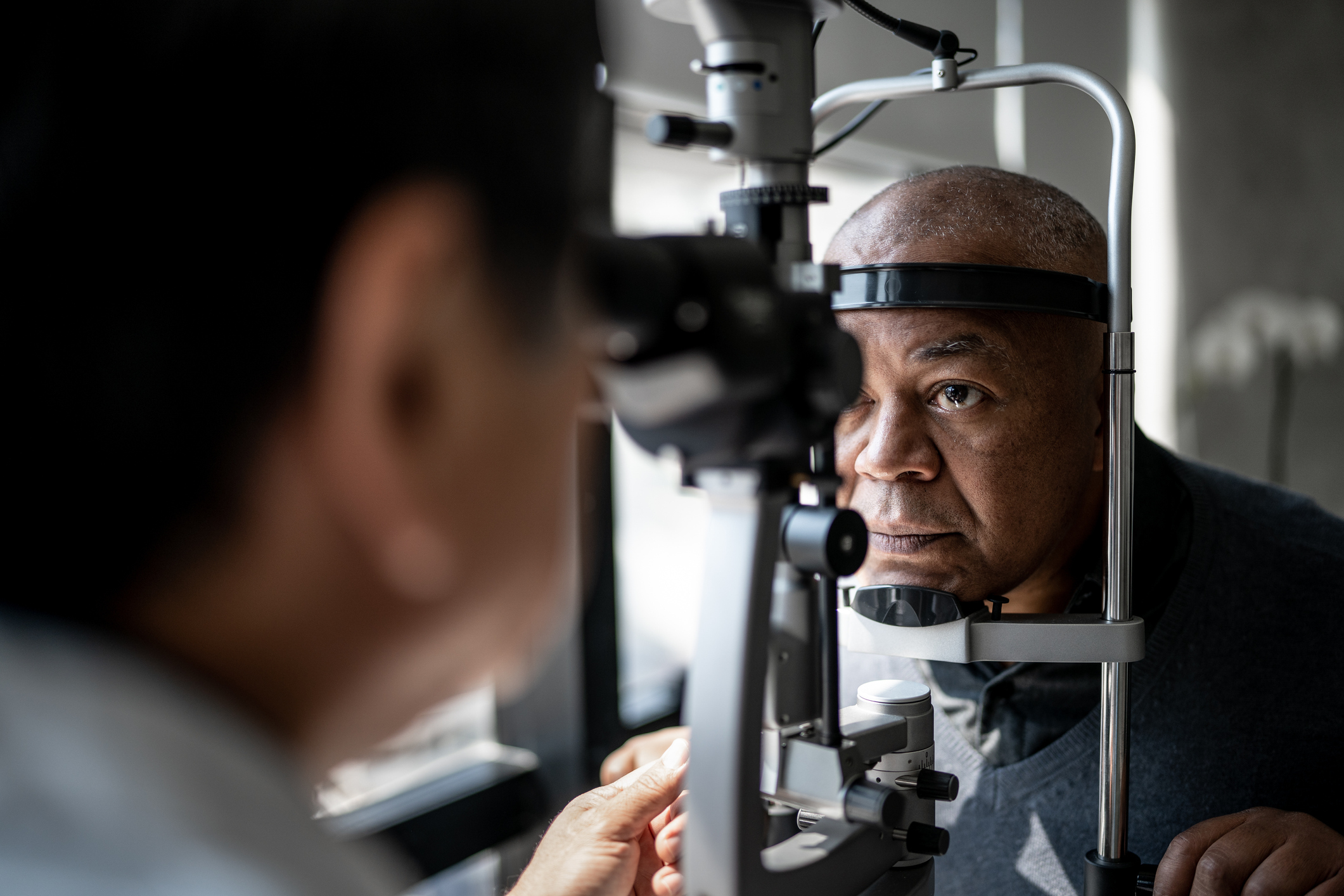 An African American man receives vision screening during an eye appointment.