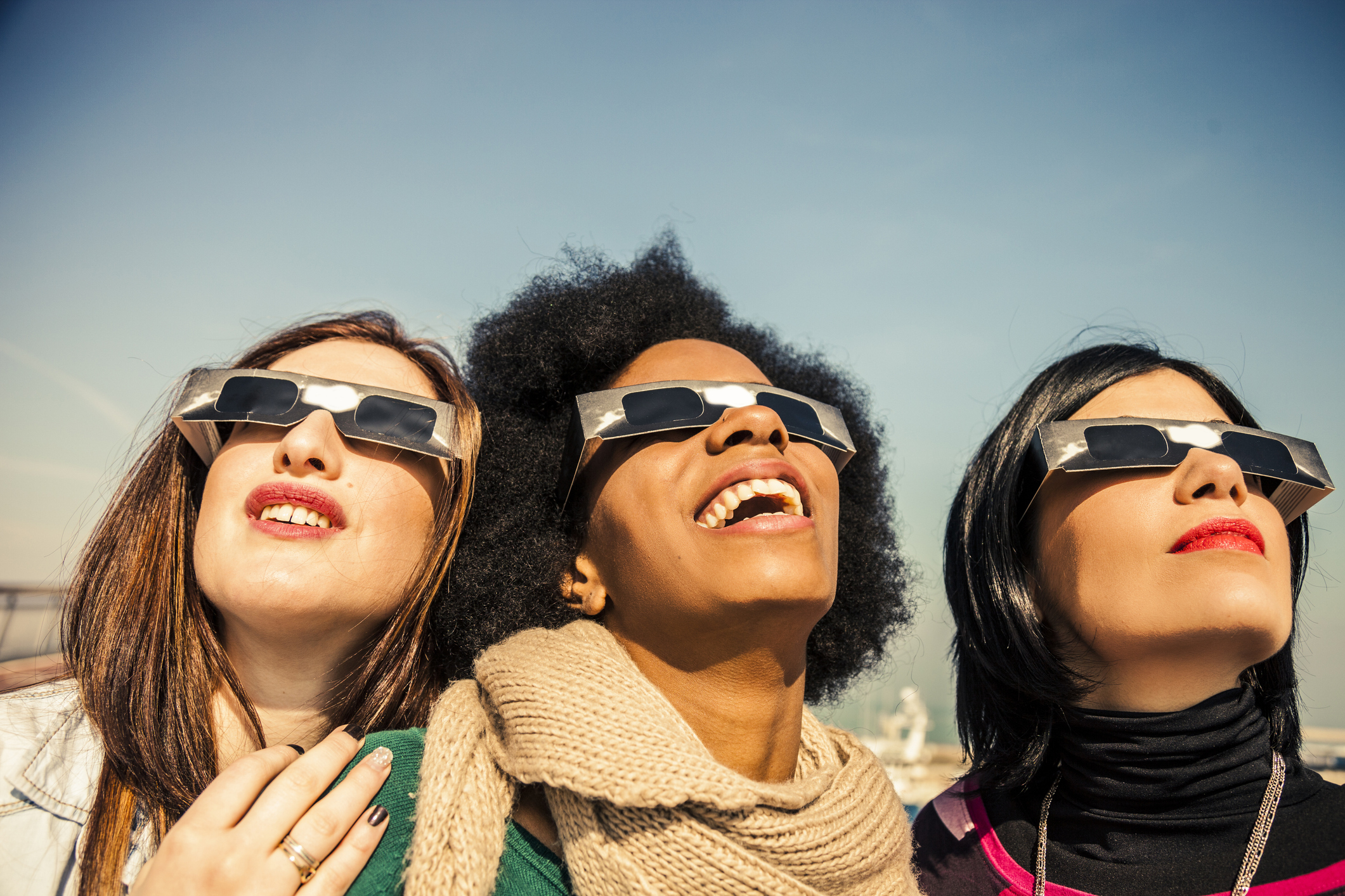 Three woman wearing specially glasses for the solar eclipse for eye safety.