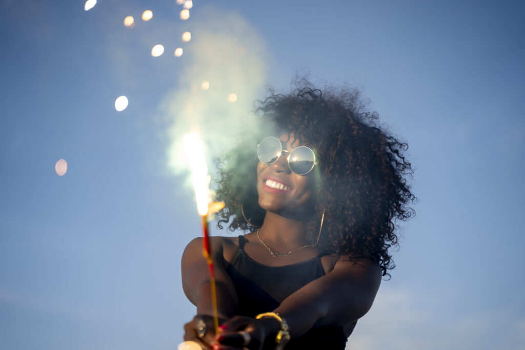 Woman holding a firework stick, wearing glasses