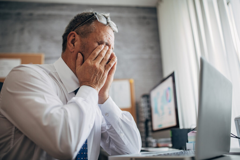 man sitting in front of computer rubbing his strained eyes