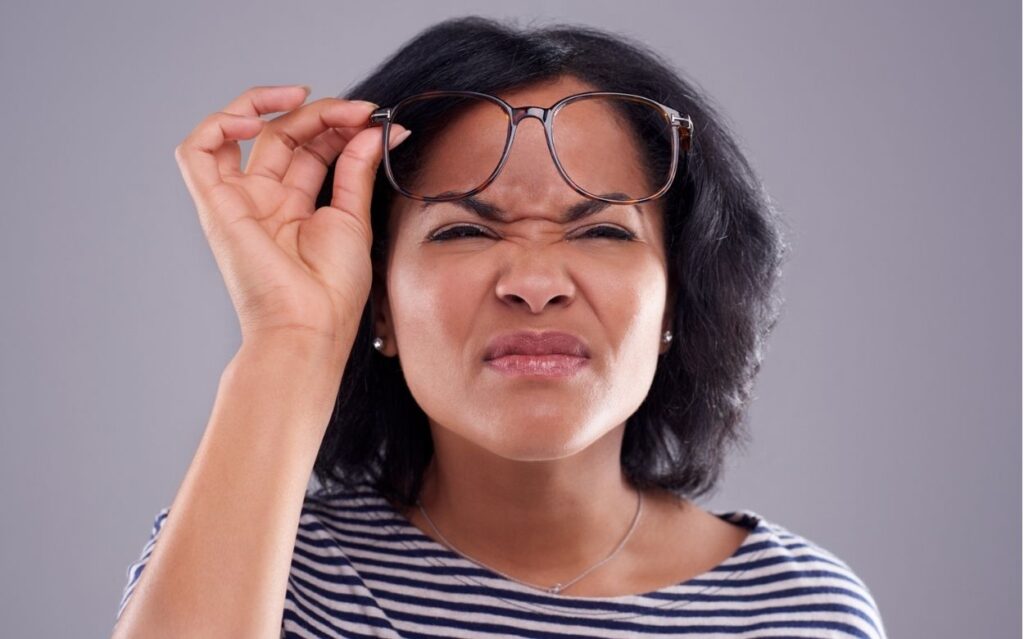 woman raising her glasses and squinting her eyes